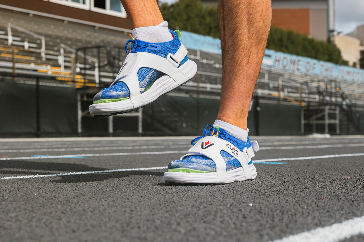 Athlete moving in CUVS Whiteout track spike covers over sprint spikes on an outdoor track.