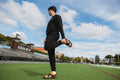 Athlete stretching on turf while wearing CUVS CV1 Blackout spike covers over orange track spikes.