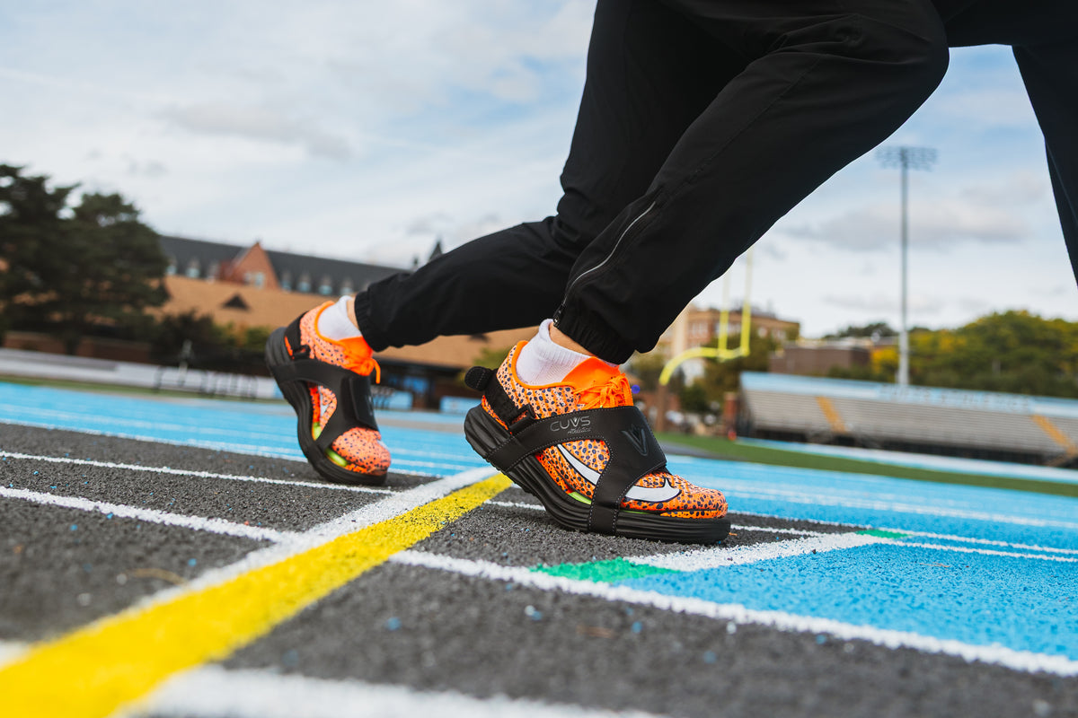 Close-up of an athlete wearing CUVS track spike covers over sprint spikes on an outdoor track.